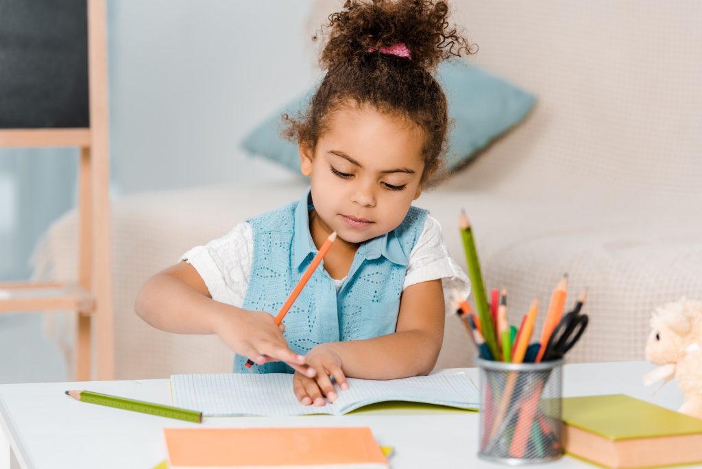 beautiful african american child studying and writing with pencil